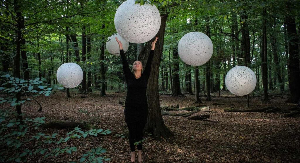 Bild von einer Frau im Wald mit weisernen Sphären