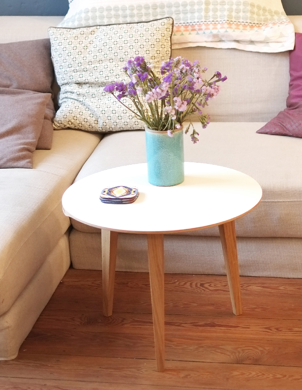 Moderner runder Couchtisch mit Vase und eleganten Sofakissen in harmonischer Living-Raumansicht