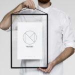 Moderner schwarzer Bilderrahmen mit geometrischem Poster, präsentiert von einem Mann im minimalistischen Interior-Design