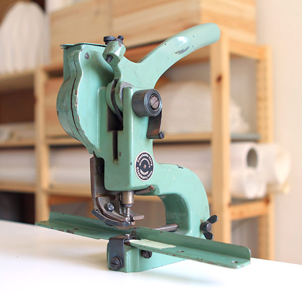 Grünes Nähargerät auf Holztisch mit weißen Handtüchern und sortierter Arbeitsstube