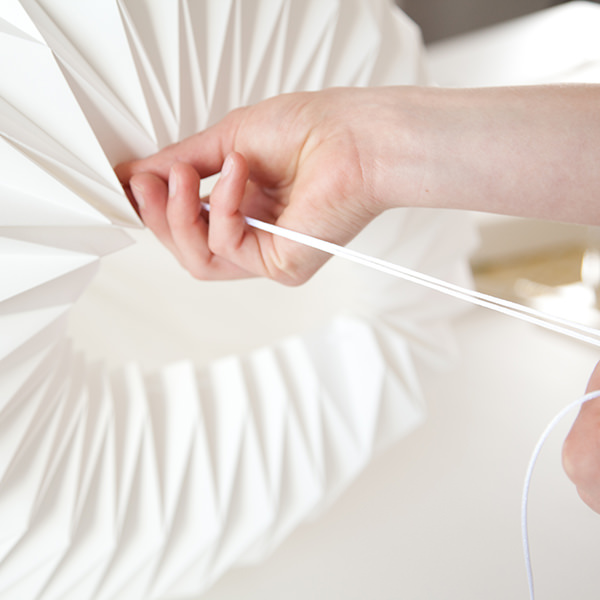 Person am Entwurf einer weißen Papierstatue mit Bleistiftarbeit