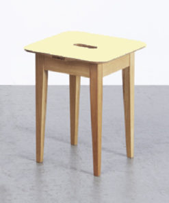 Gelber Hocker aus Holz auf greylisierter Fläche