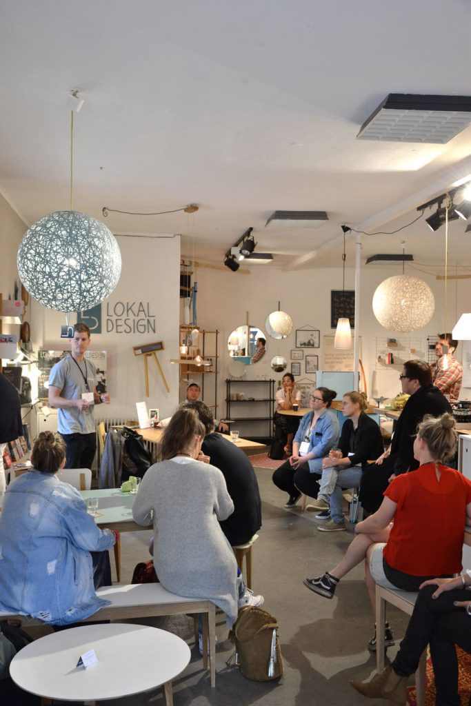 Event im lokaldesign Concept Store mit Besuchern bei Präsentation in modernem Raum mit Pendelleuchten und Holzmöbeln