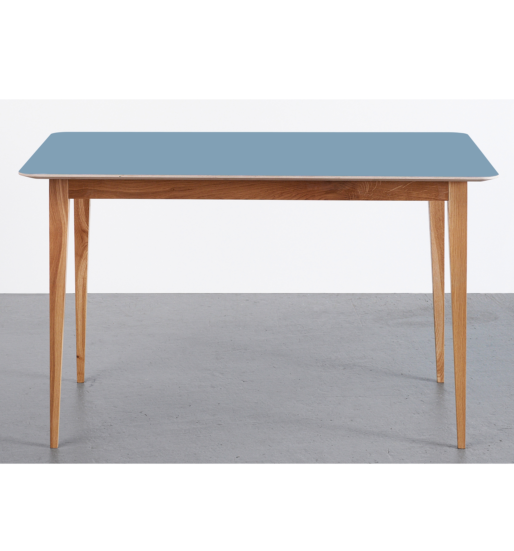 Eleganter Esstisch im skandinavischen Design mit blaugrauer Tischplatte und Eichenholzbeinen auf grauem Hintergrund