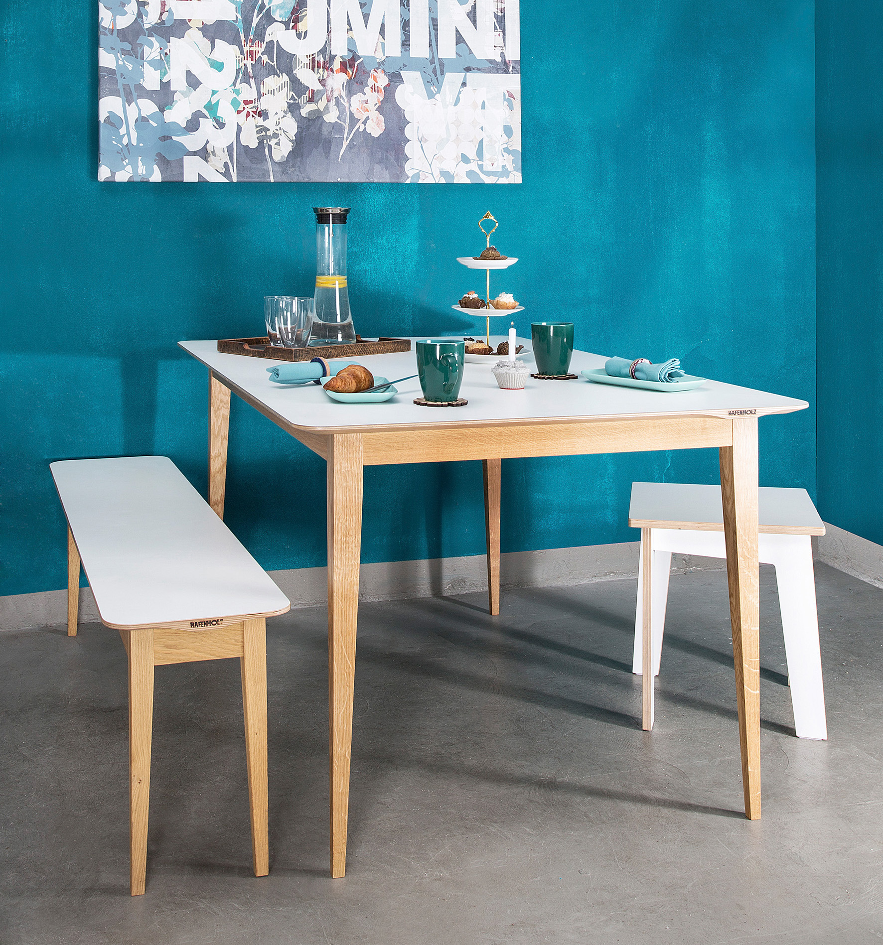 Modernes Esszimmer-Set aus heller Eiche mit weißer Tischplatte vor türkisblauer Wand auf lokaldesign.de