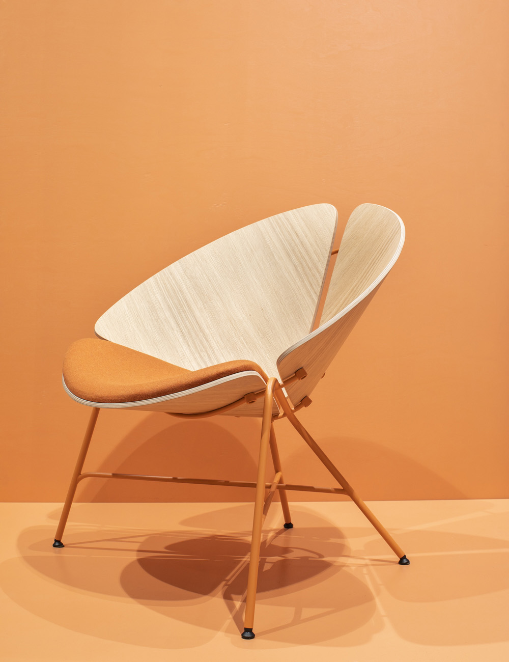 Moderner Wicker-Sessel auf hartholzgetappter Fläche mit orangefarbenem Raumhellészten ambiente
