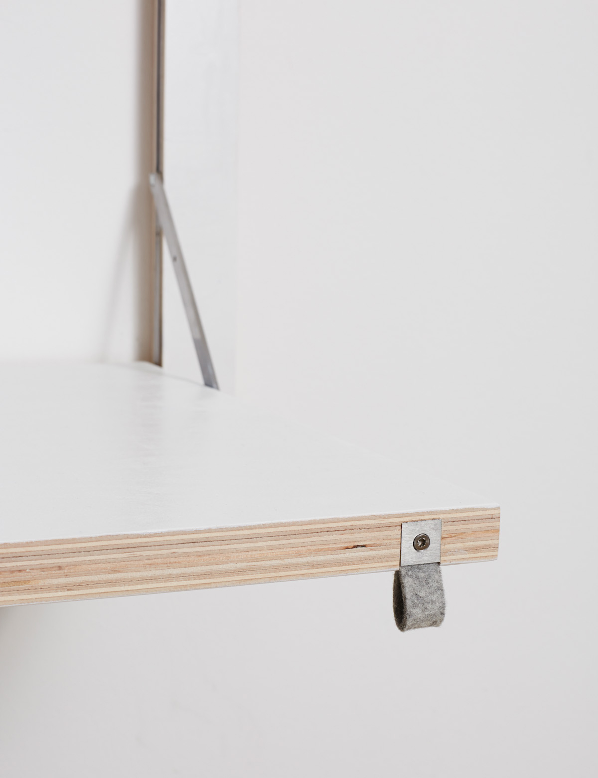 Minimalistische Wandgarderobe aus Naturholz mit metallischem Träger auf weißer Wand