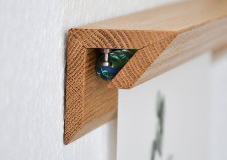 Elegantes helles Holz-Wandregal mit irisierendem Kristallstein an der Seite