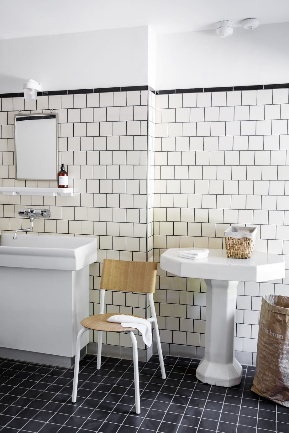 Nachhaltiges Badezimmer in skandinavischem Design mit TIPTOE Holzstuhl, weißen Waschbecken und Rattan-Körben