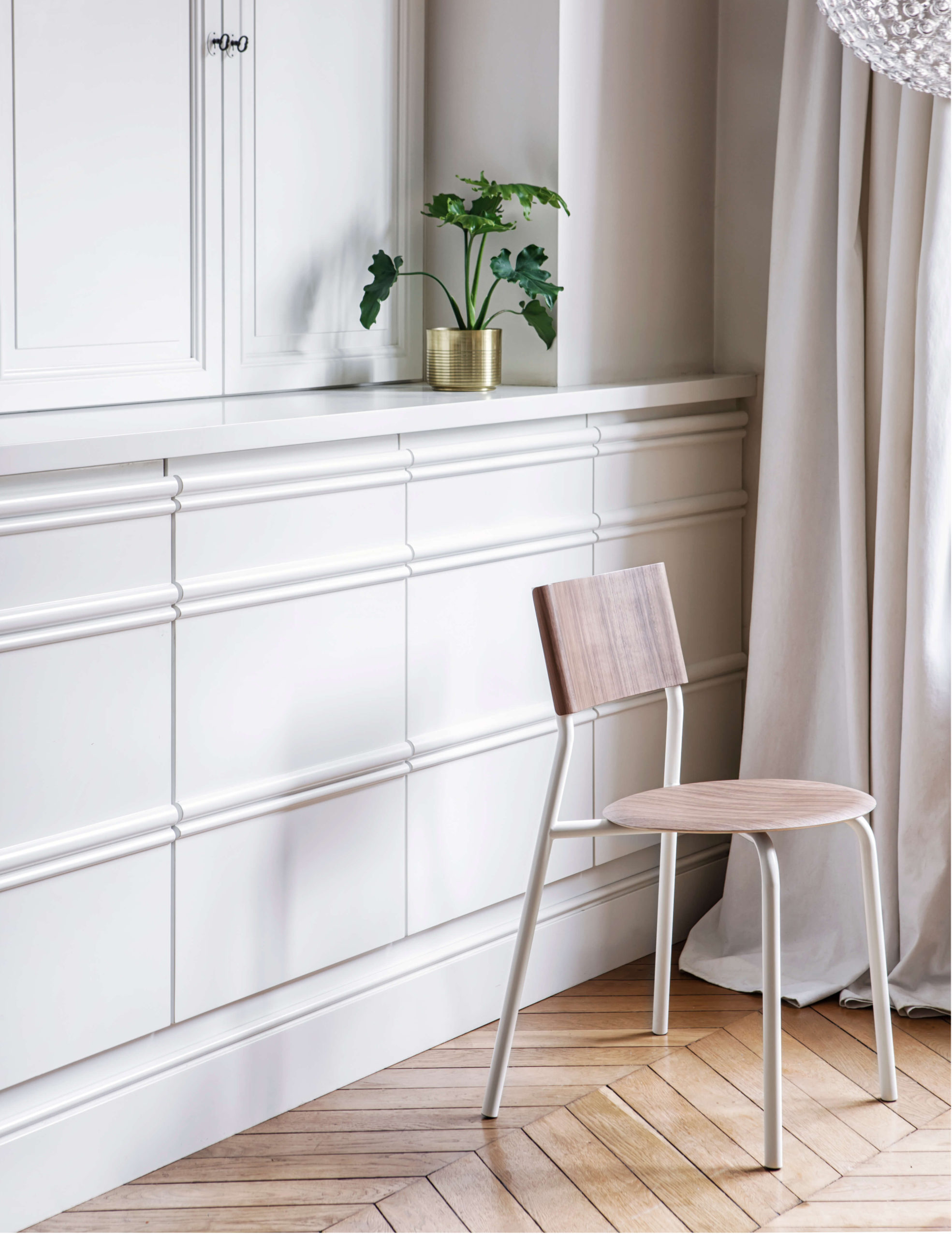 Weißer Raum mit bernsteinfarbenem Designstuhl und Pflanze auf Regal