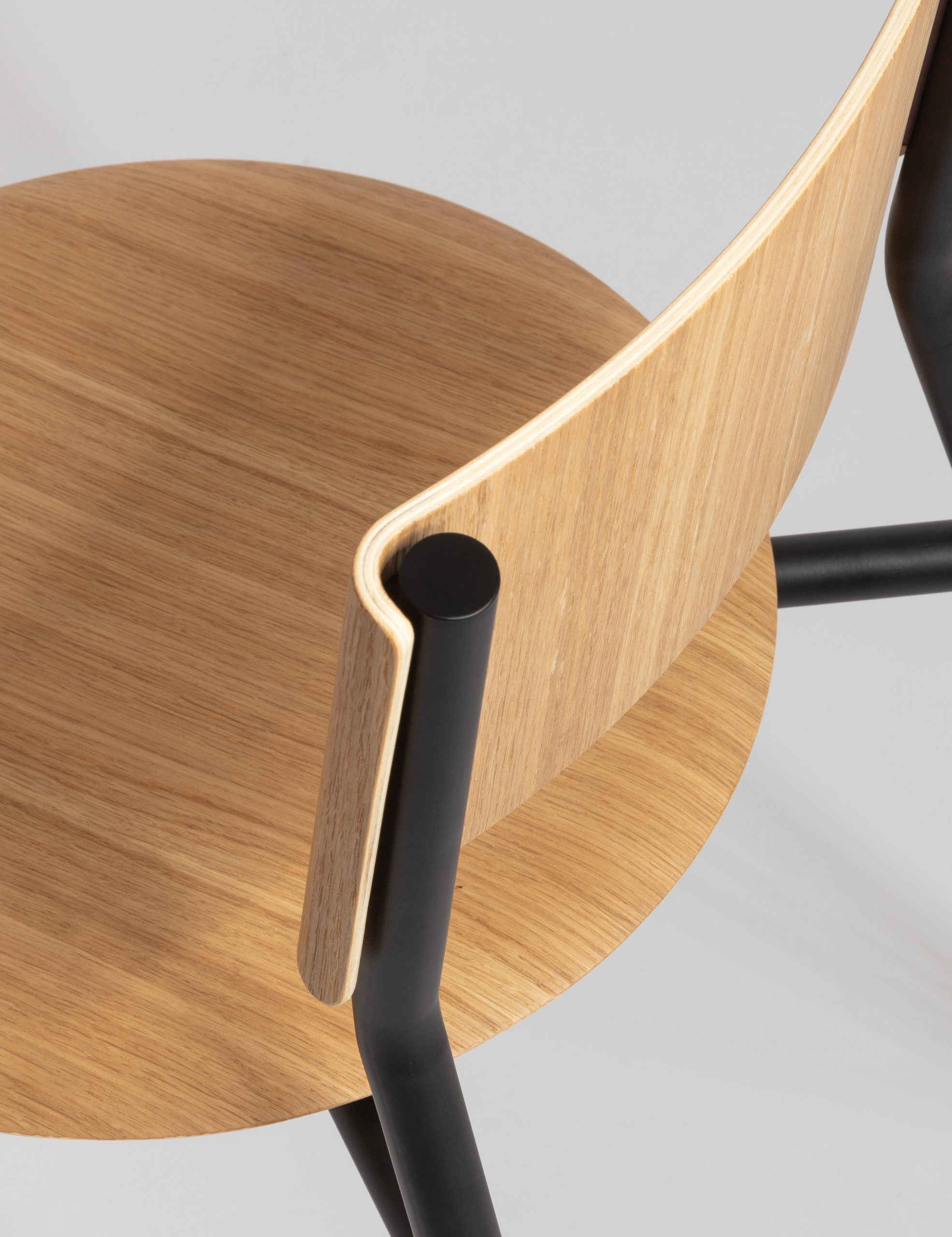 Moderner Designstuhl mit heller Eiche und schwarzen Metallgestell auf grauem Hintergrund