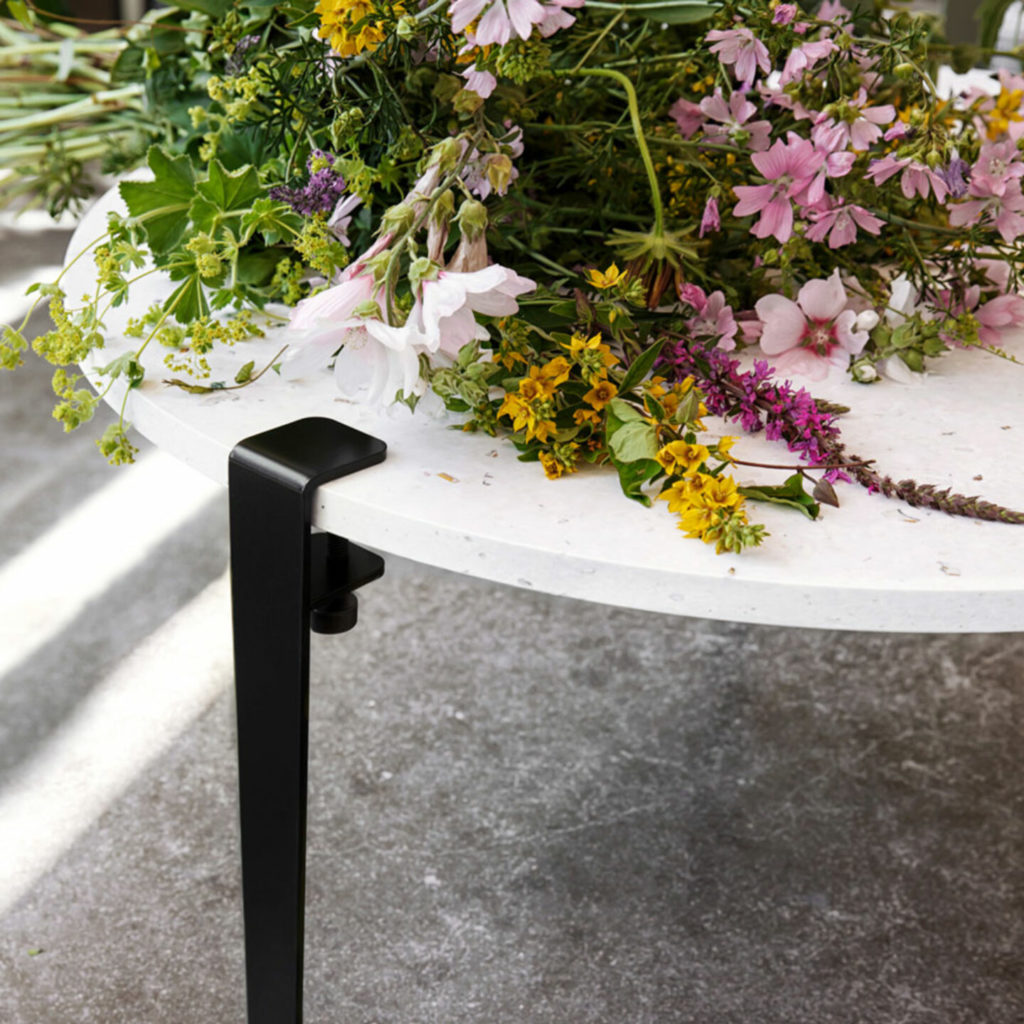 Nahaufnahme eines schwarzbezogenen Couchtisches mit Blumen