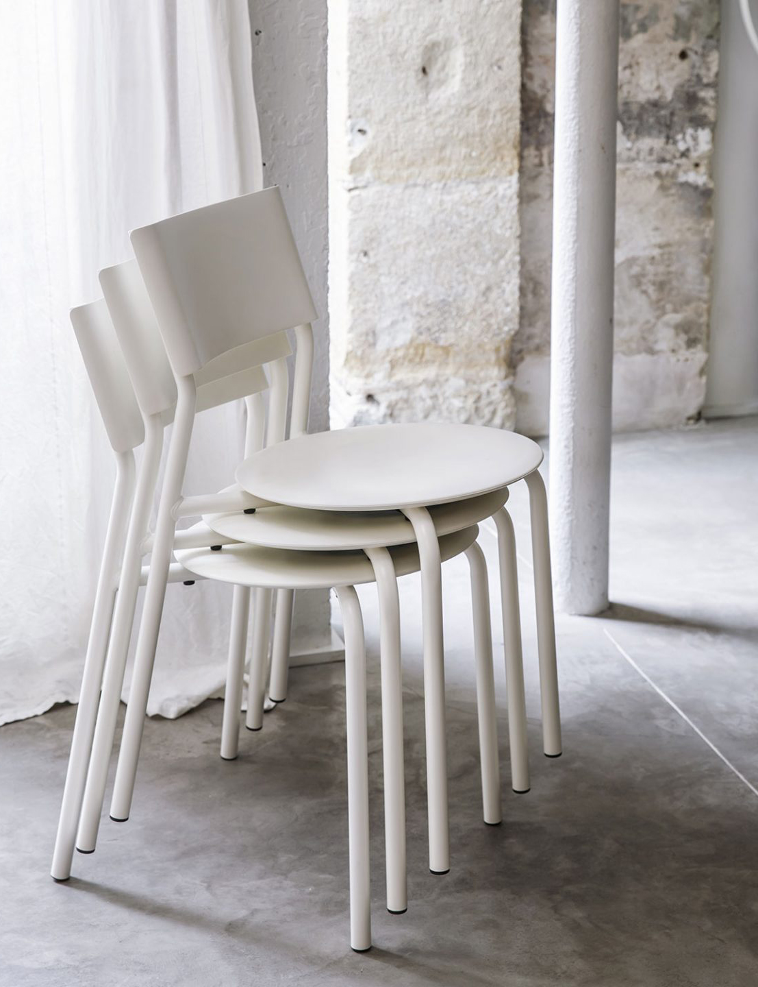 stapelbare Designer-Stühle in Weiß mit geschwungener Rückenlehne im industriellen Loft-Setting