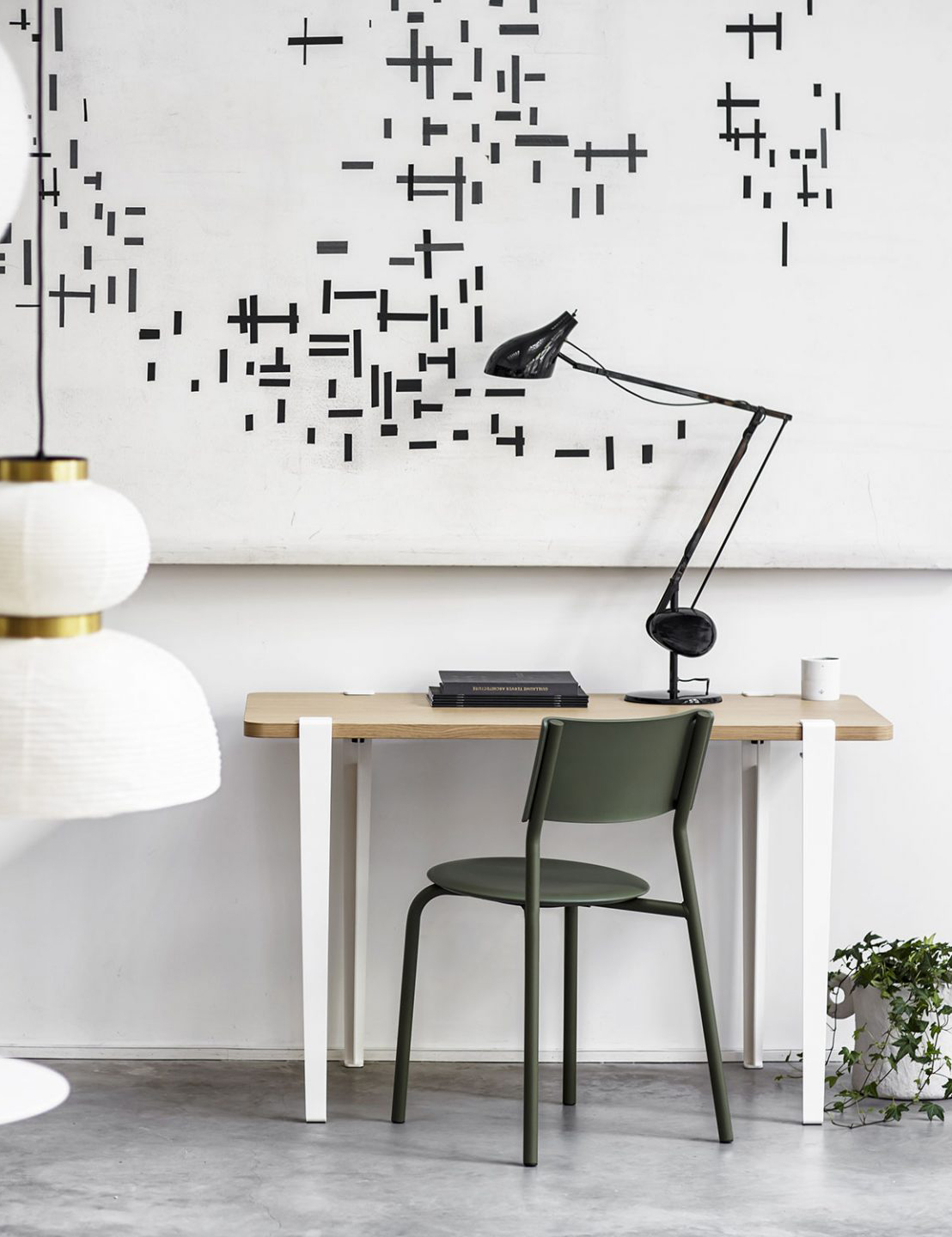Minimalistisches Homeoffice-Setup mit grünem Stuhl, Holzschreibtisch und eleganter Gelenkleuchte