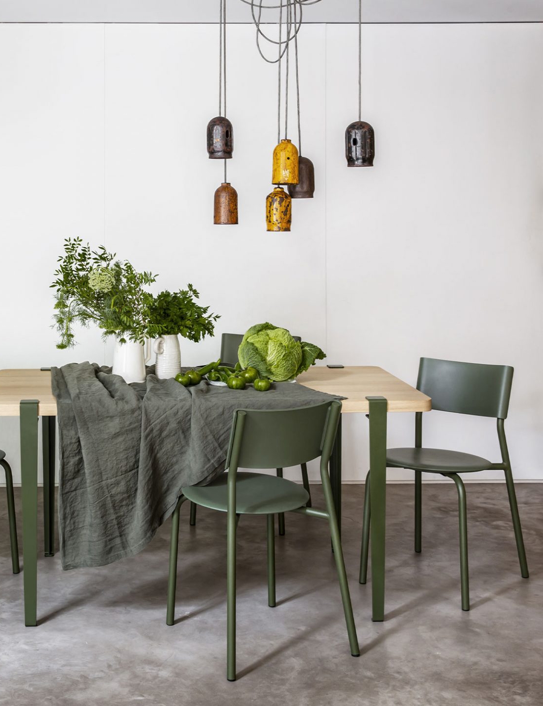 Moderner Esstisch aus Eiche mit grünen Designer-Stühlen und zeitgenössischer Pendelleuchte in stilvollem Interieur