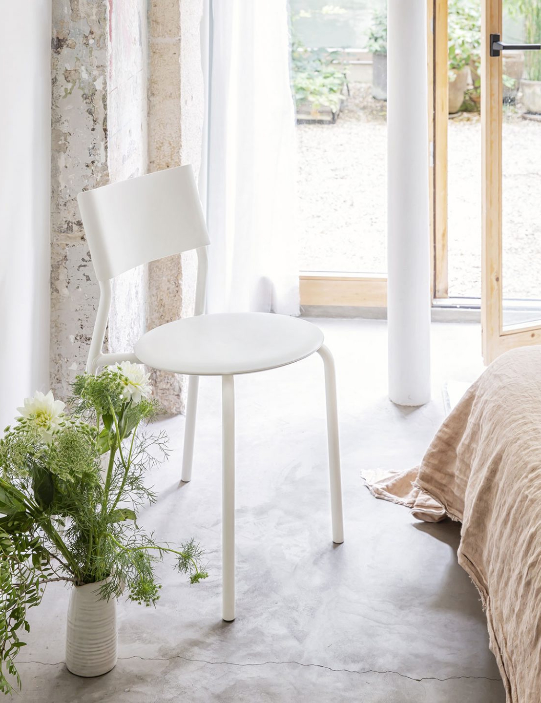 Weißer Tiptoe Stuhl im Wohnzimmer mit Bett und Topfpflanze für ein einladendes Ambiente