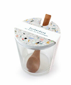 Holzlöffel und Glasbecher auf einem Brett in einer klaren Umgebung