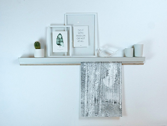 Minimalistisches Regal mit Bilderrahmen und Fotografie auf weißer Wand