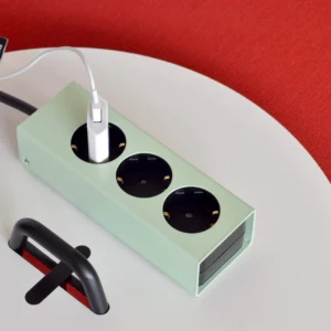 Moderne Steckdosenleiste mit drei Stecker in mintgrüner Farbe auf weißem Tablett
