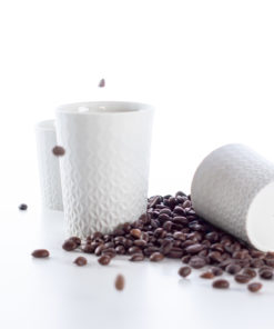 Elegante weiße Kaffeetassen und Kaffeebohnen auf minimalistischem Hintergrund