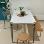 Ellie Tischplatte aus nachhaltigem Design, weißer Tisch mit Holzdecke, Vase und Kanne, umgeben von weißen Stühlen im