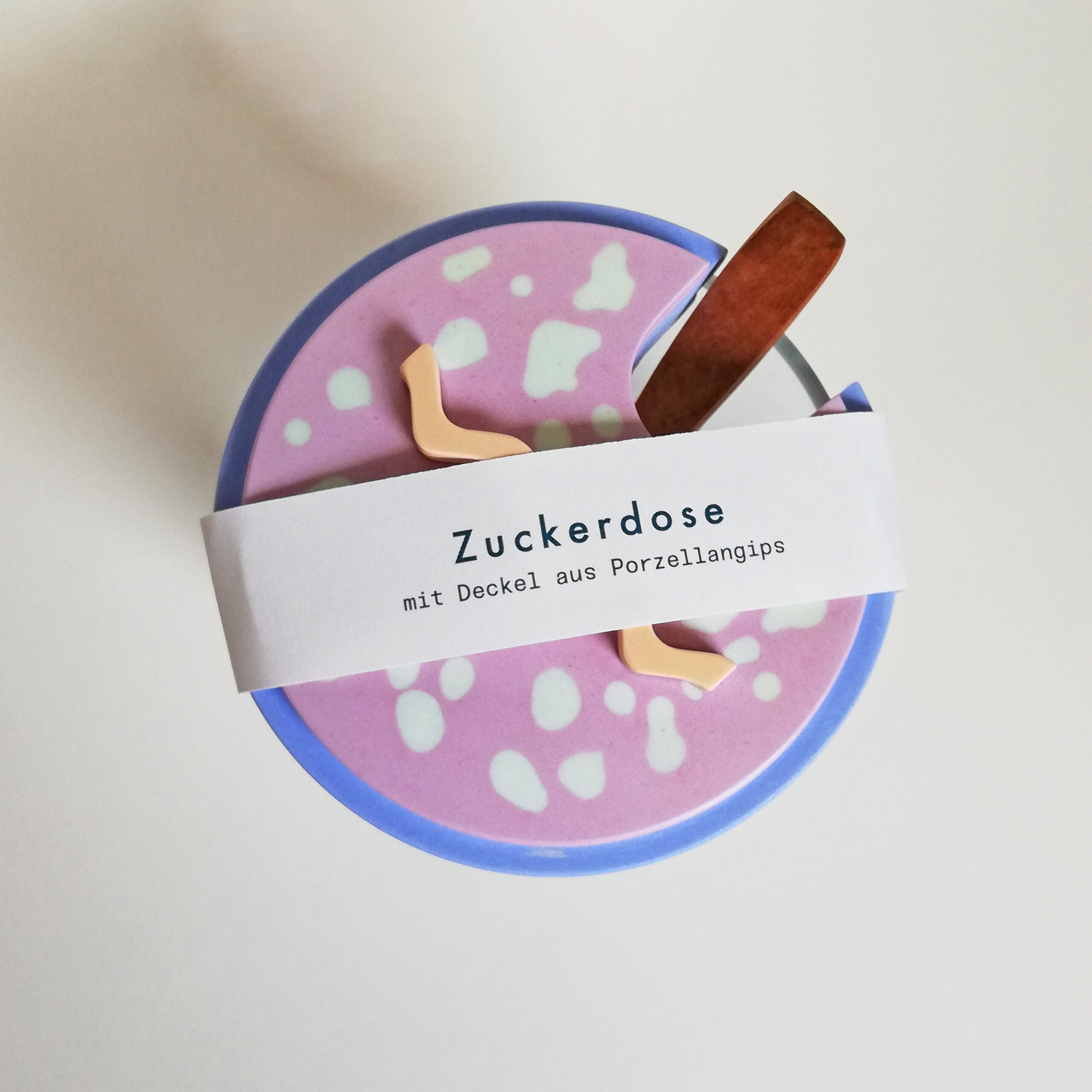 Zuckerdose aus Porzellan in Rosa mit weißen Punkten und blauem Rand, mit Holzlöffel und Servierer