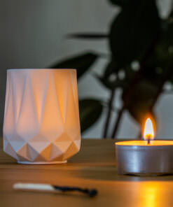 Weiße Kerze auf Holztablett mit Vase und Pflanze in gemütlicher Atmosphäre