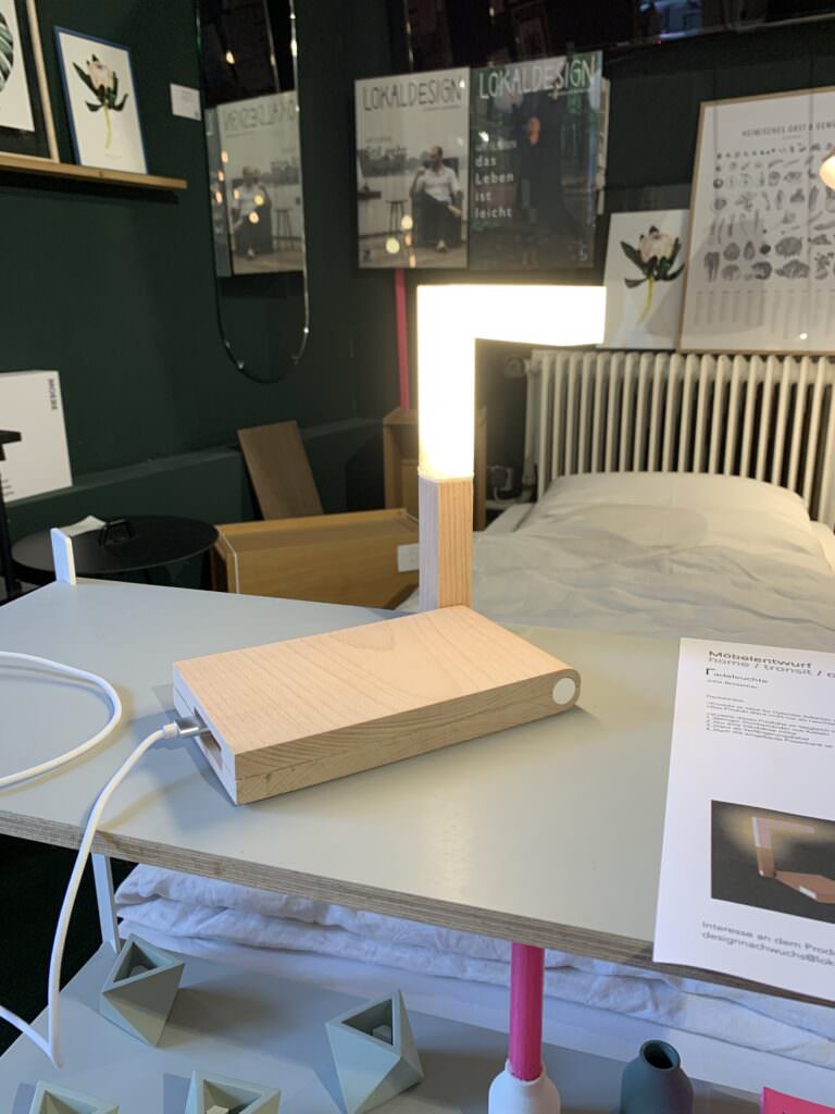 Moderner Concept Store mit minimalistischer Holzleuchte und Wohnaccessoires in dunklem Ambiente