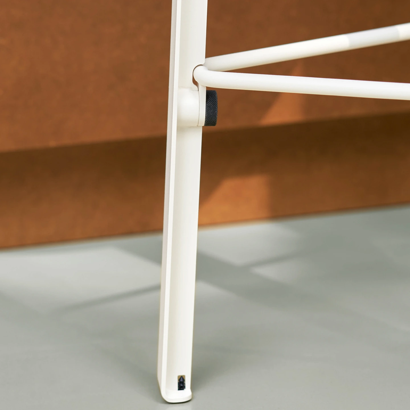 Weisses Designmoebel mit schwarzen Griffen vor terrakottafarbener Wand