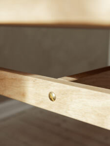 Hochwertiges Möbel-Detail mit hellen Holzrahmen und Messingschraube