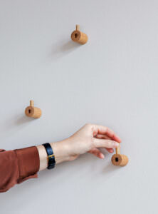 Dreierreihe von hellem Holz-Wandhaken mit minimalistischem Design auf weißer Wand