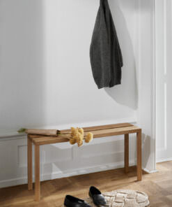 Holzgepolsterte Bank mit Jackett und Blumen in weißer Wandansicht