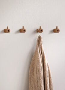 Vier minimalist Wandhaken aus Eichenholz an cremefarbener Wand mit beigem Leinentuch