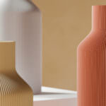 Drei moderne Keramikvasen mit vertikalen Rillen auf minimalistischem Hintergrund in warmen Farben