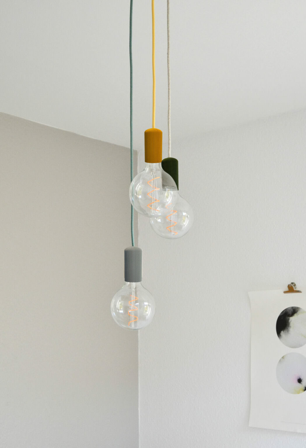 Moderne dreifarben Pendelleuchten mit gläsernen Kugeln und geriffeltem Metall in minimalistischer Raumgestaltung