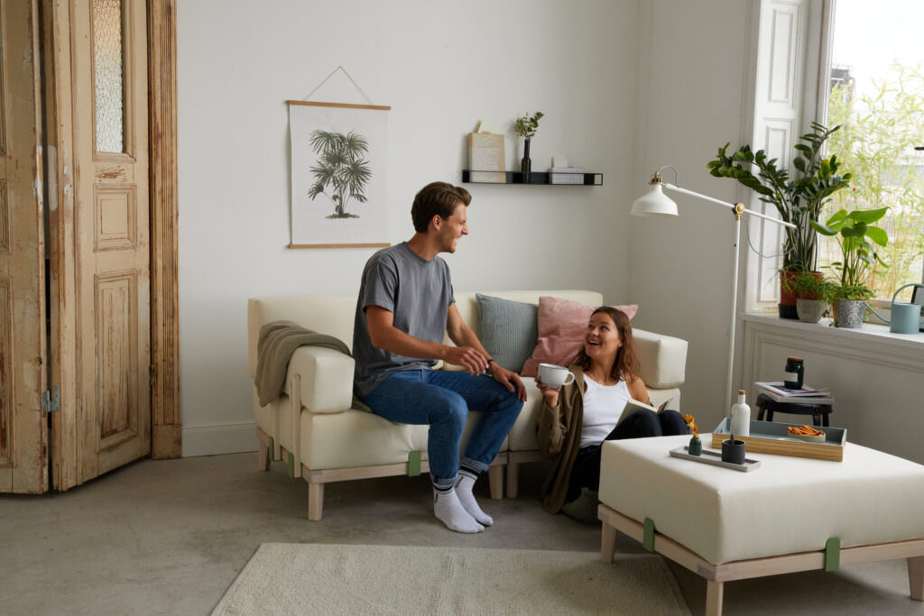 Junge Frau und Mann sitzen entspannt auf weissem Sofa