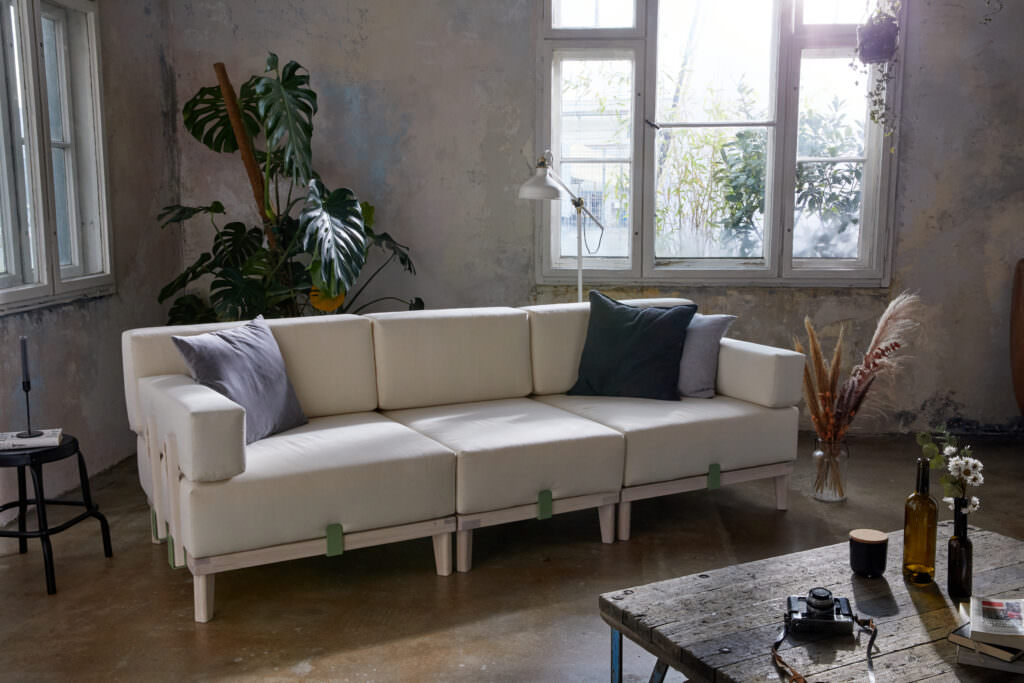 Modulares Sofa in cremeweiß mit grünen Verbindungselementen im industrialen Raum