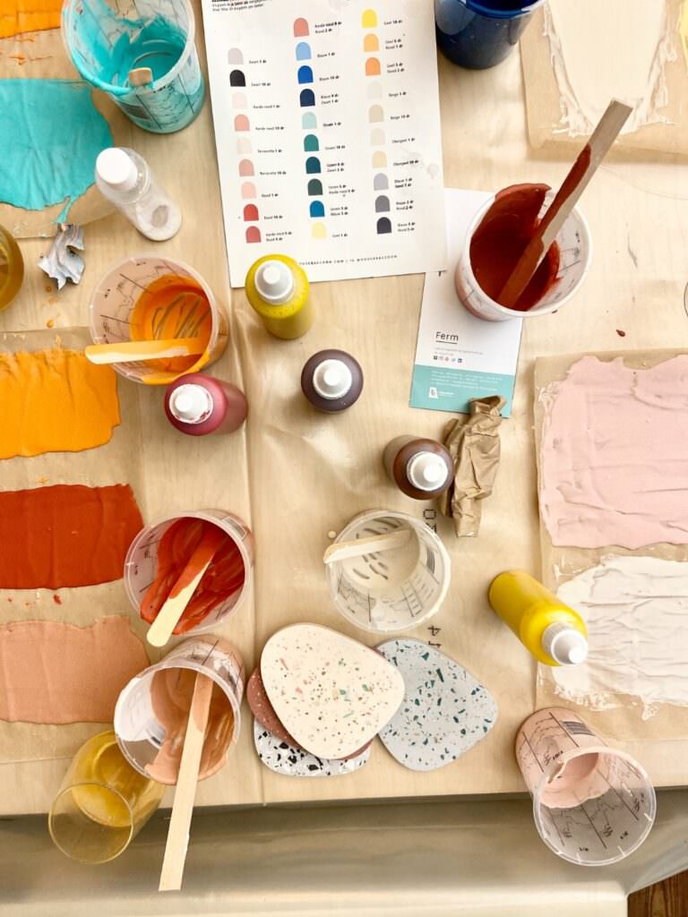 Vielfältige Farben und Materialien auf einem Tisch mit Pinsel, Farbkugeln und Tüchern in kreativem Workshop-Ambiente