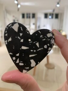 Person hält weiße und schwarze Marmor-Heart-Kugel in gemütlichem Raum mit Stuhl und Tisch, zeigt nachhaltiges Interior-Design