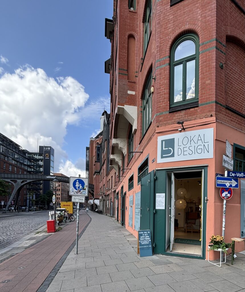 Rote Fassade mit Fenstern, umgeben von Designmöbeln, Wohnaccessoires und Materialien für modernes Interior in Hamburg