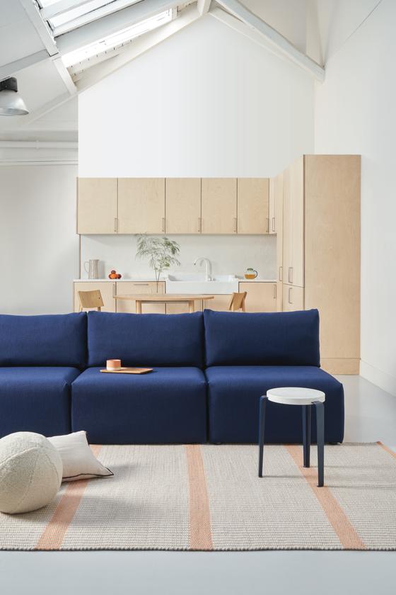 Blaues modulares Bridge Sofa im Wohninterior mit Tisch, Wohnaccessoires – modernes Designmöbel aus nachhaltiger Produktion