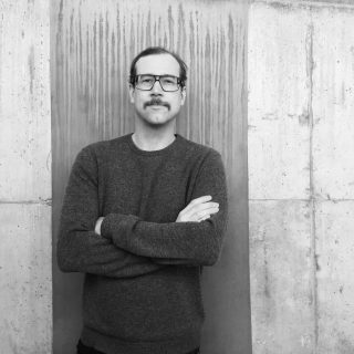 Klassischer Woll-Strickpullover auf rohem Betonhintergrund in minimalistischem Setting